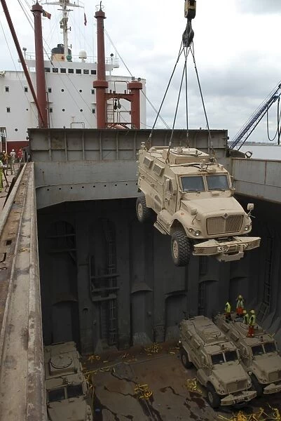 A harbor crane lifts a mine-resistant, ambush-protected vehicle from the hull of