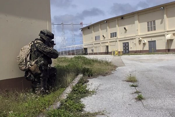 A Marine posts security as a team of Marines prepare to enter an enemy warehouse