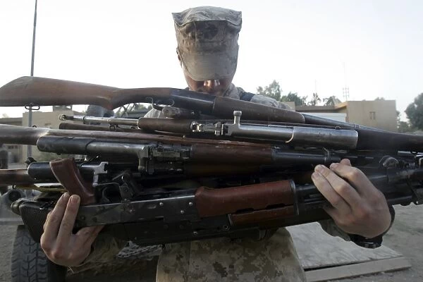 A marine readies 80 pounds of enemy rifles seized
