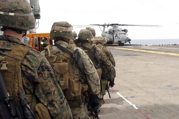 Marines and sailors progress to board a CH-53E Super Stallion