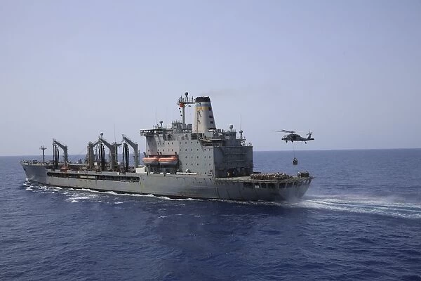 An MH-60S Sea Hawk conducts a vertical replenishment with USNS Laramie
