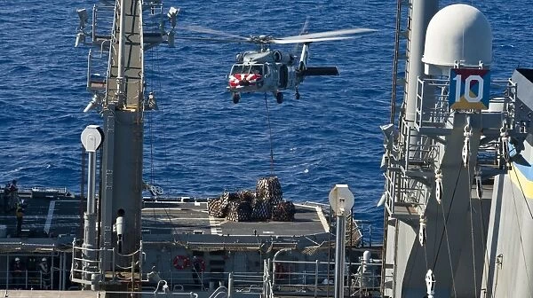 An MH-60S Sea Hawk delivers supplies to the flight deck of USS Mobile Bay