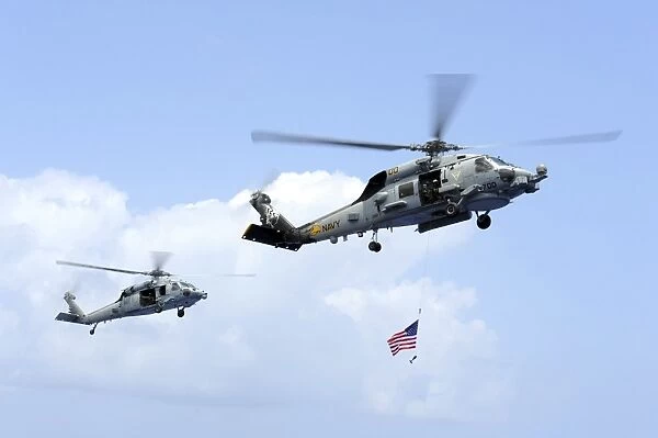 An MH-60S Sea Hawk helicopter follows behind an MH-60R Sea Hawk
