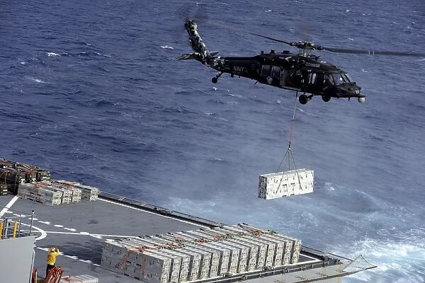 An MH-60S Sea Hawk helicopter picks up ammunition from USNS William McLean