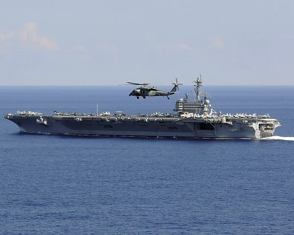 An MH-60S Seahawk helicopter flies over USS George H. W. Bush