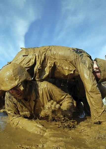 A midshipman crawls through fellow plebes in an obstacle course