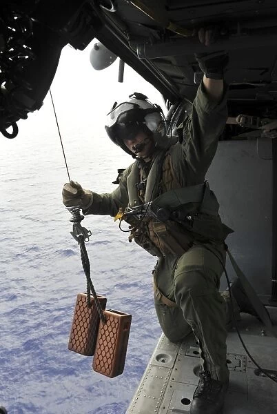 Naval Aircrewman conducts a search and rescue drill on an MH-60S Sea Hawk