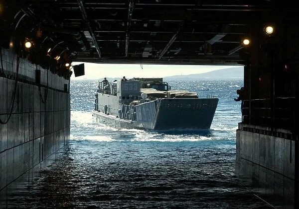 A Navy Landing Craft Utility approaches the well deck of USS Tarawa off the coast