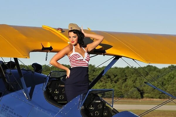 Patriotic pin-up girl standing inside the cockpit of a Stearman biplane