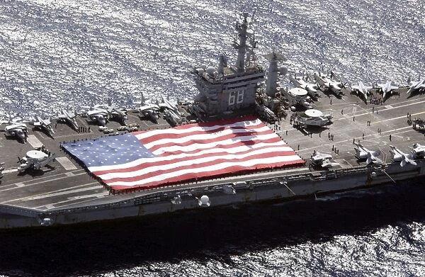 Personnel participate in a flag unfurling rehearsal on the flight deck aboard USS Nimitz