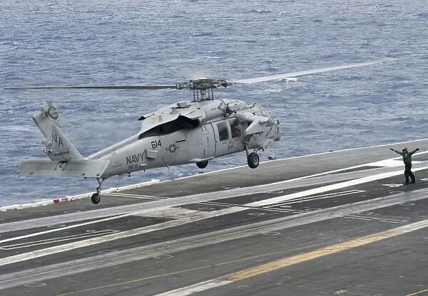 A Sailor directs an MH-60S Sea Hawk to land on the flight deck of USS Carl Vinson