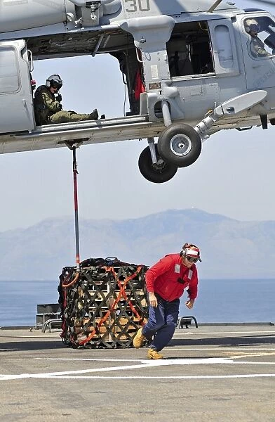 Seaman hooks a pallet to an MH-60S Sea Hawk helicopter