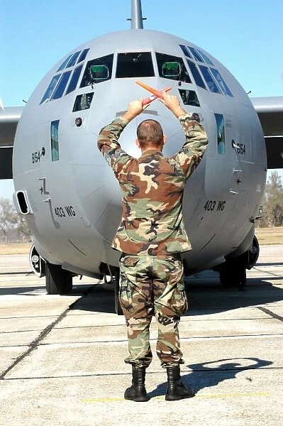 Senior Airman guides a C-130 Hercules into its parking spot