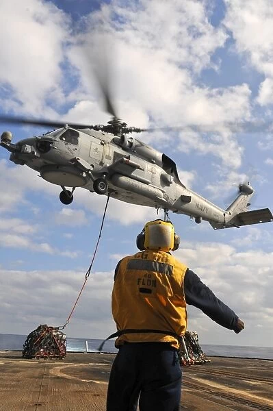 An SH-60B Sea Hawk helicopter releases cargo on the flight deck of USS Anzio