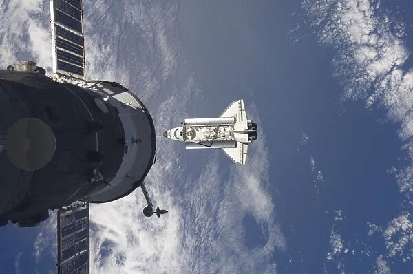 Space Shuttle Atlantis and a Russian spacecraft backdropped by a blue and white Earth