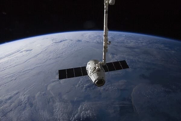 The SpaceX Dragon cargo craft is suspended in the grasp of the Candarm2