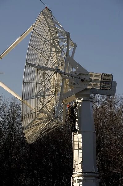 A technician climbs up a large radio telescope antenna