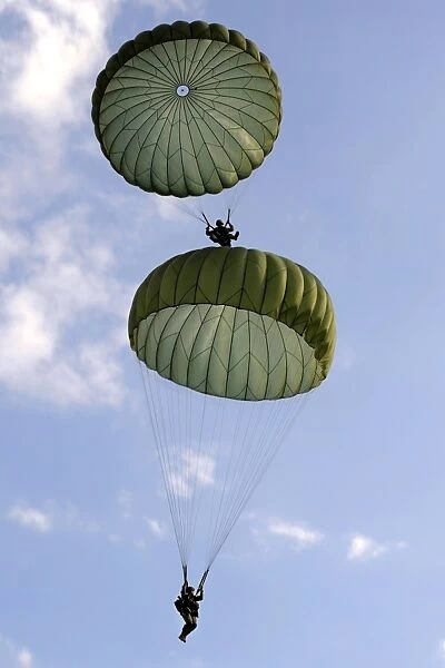 U. S. Army Soldiers parachute down after jumping from a C-130 Hercules