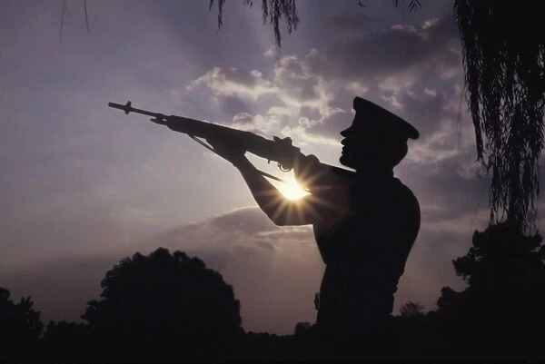 A U. S. Marine Honor Guard rifleman performs a gun salute during sunset