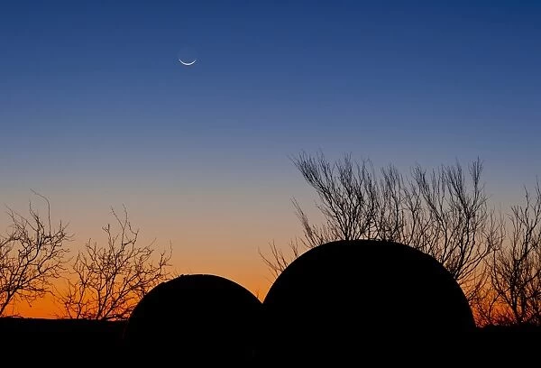 A young moon sets over two domed observatories, Crowell, Texas