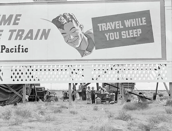 Billboard along U.S. 99 behind which three destitute families... Kern County, California, 1938. Creator: Dorothea Lange