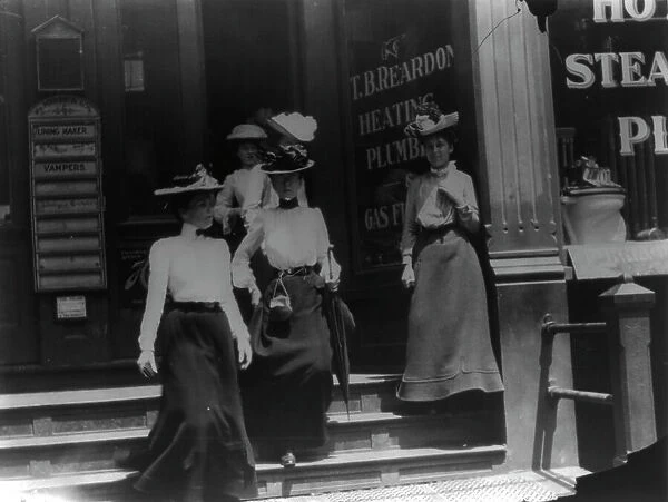 Women coming from work, Cal.?. Store window reads T.B. Reardon, heating and plumbing, 1903. Creator: Frances Benjamin Johnston
