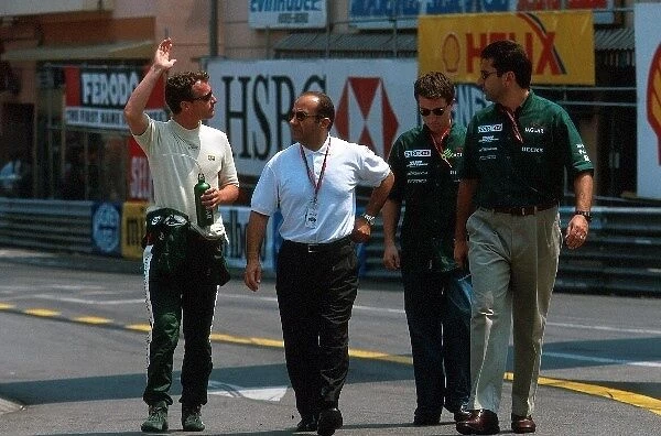 Formula One World Championship: Eddie Irvine Jaguar Cosworth R1 waves to the crowd as he walks to the pits with Jac Nasser, President of Ford