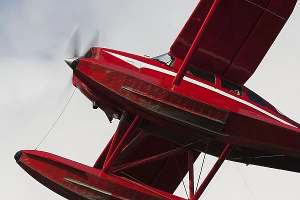 Low Angle View Of A Red Float Plane Against A Cloudy Sky; Alaska, United States Of America