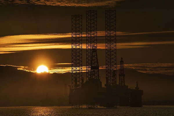 Oil Drilling Rigs Out In The Ocean With A View Of The Coastline And Golden Sunset; Cromarty, Invergordon, Scotland