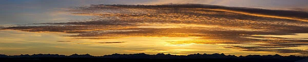 Panorama Of Colourful Dramatic Clouds At Sunset With Silhouette Of Mountains Along The Horizon; Calgary, Alberta, Canada