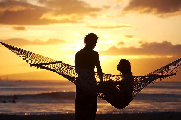 USA, Hawaii, Oahu, Silhouette of woman in hammock and man standing next to her in Kapiolani Park; Waikiki