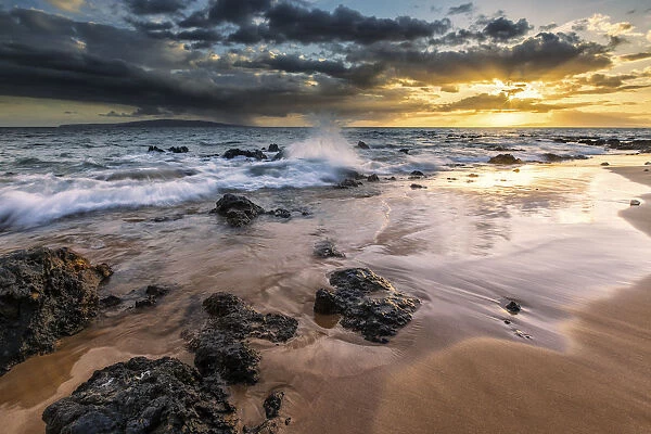 Water Splashing On The Beach With A Golden Sunset Over The Ocean; Hawaii, United States Of America