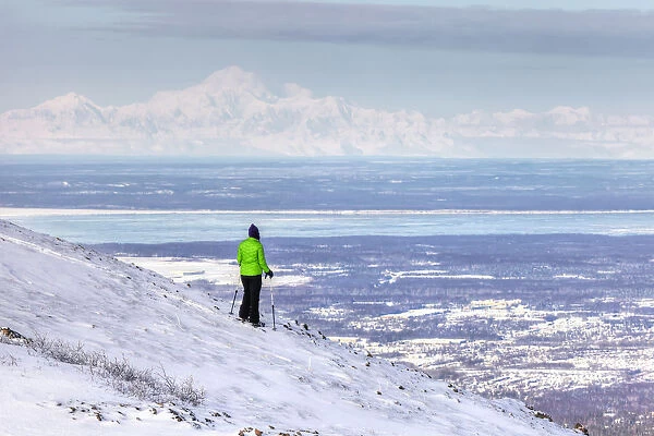 Woman snowshoer taking in the view of Mt. McKinley (Denali) from Blueberry Hill at the Glen Alps area of Chugach State Park, Anchorage, Southcentral Alaska, Winter, HDR