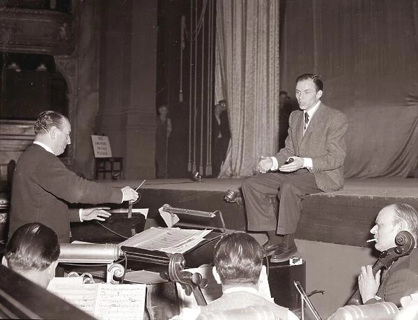 American singer and film star Frank Sinatra sitting on stage during rehearsals at