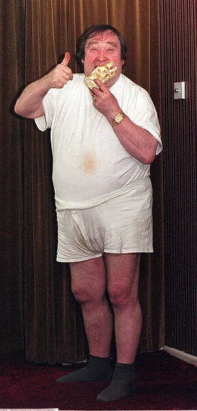 Bernard Manning comedian eating a Walls Arctic Roll dessert. September 1997