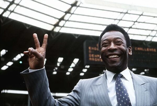 Brazillian football legend Pele gives the peace sign while standing on the pitch at