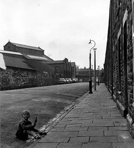 Cardiff - Old - Adamsdown - A young child sits in the gutter in Cycle Street with