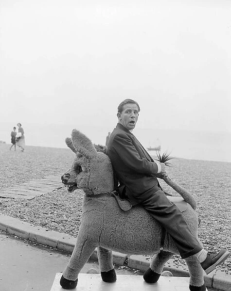 Comedian and actor Norman Wisdom photographed on Brighton Beach on a stuffed donkey