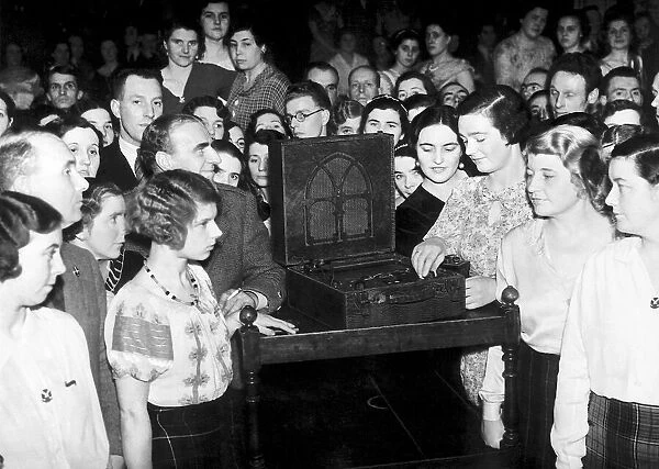 A crowd of people huddle around a wireless to listen to the Abdication Speech of King