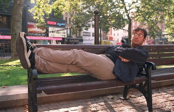 DAVID BADDIEL, COMEDIAN AND WRITER - F  /  L, SEATED WITH FEET UP ON PARK BENCH