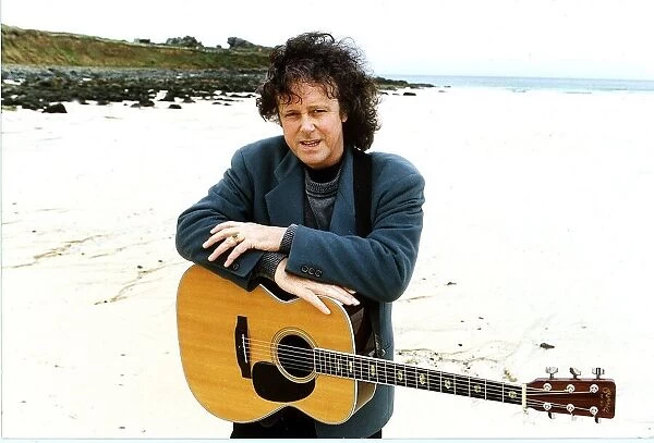 Donovan Pop Star of the 60s pictured at a beach with his guitar hanging around his neck