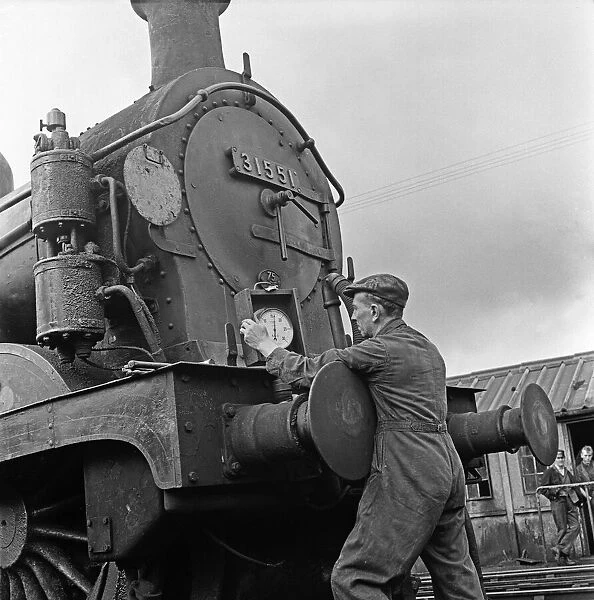 An engineer waters a H Class 0-4-4T locomotive at the Tunbridge engine shed. Circa 1960