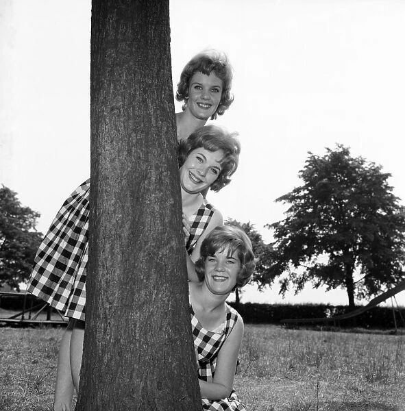 England Sisters hiding behind a tree: The Sisters from left: Hazel, 18, Julie, 19, Betty