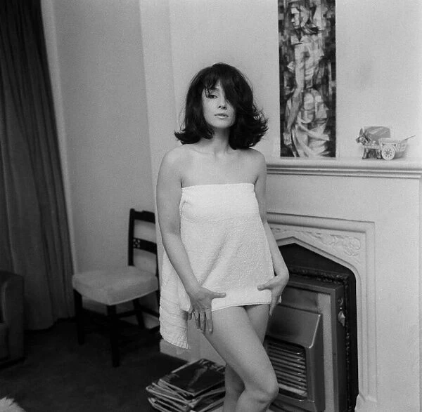 English actress Shirley Anne Field standing beside a fireplace dressed only in short