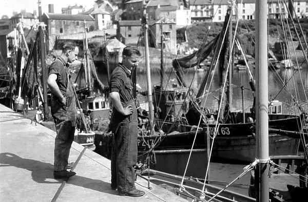 Fisherman on the quayside look longing at the boats of Fishing fleet at Brixham, Devon
