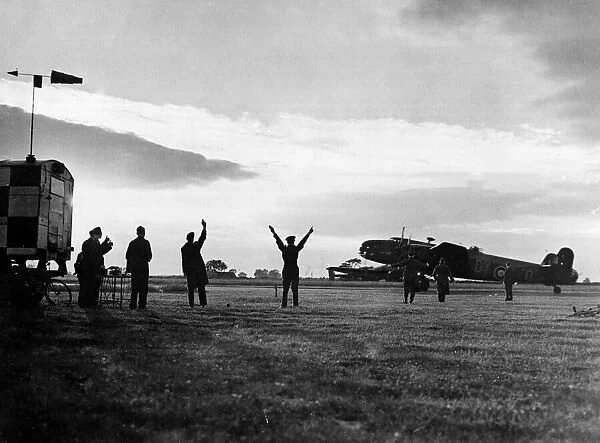 The group captain commanding officer of an RAF station signals a Halifax bomber to begin