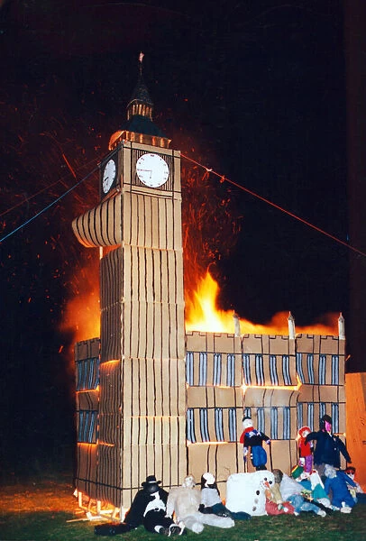 Guys sit next to a bonfire modelled to look like the Houses of Parliament
