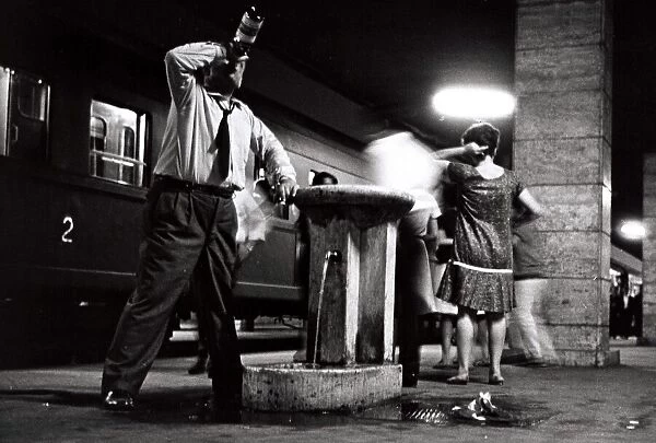 A happy man leans against the drinking fountain at Naples Station - June 1962