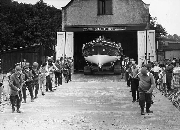 Hauling on two guide ropes, the launching crew steady the Ferryside Lifeboat as it runs
