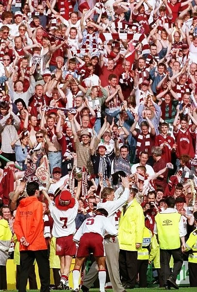 Heart of Midlothian footballers show off the Scottish Cup trophy to jubilant fans on a